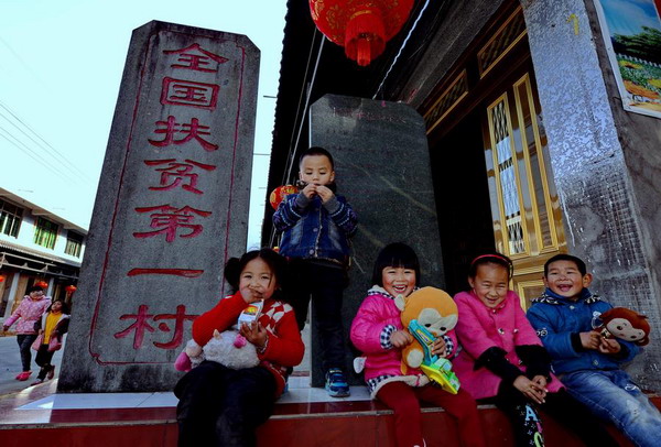 Children of Se ethnic group sit in front of a monument that reads China's No. 1 Poverty Relief Village at Chixi Village, Panxi town, Fuding city in East Chinas Fujian province, Feb 14. The village has shaken off poverty thanks to assistance from Party and government officials at all levels over the past 30 years. (Photo/Xinhua)