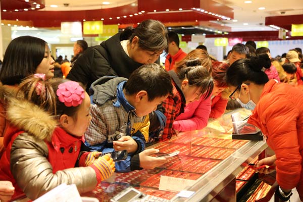 Potential buyers examine gold items at a jewelry store in Xuchang, Henan province. China's consumption growth is likely to witness a slowdown in 2015.(Provided to China Daily)