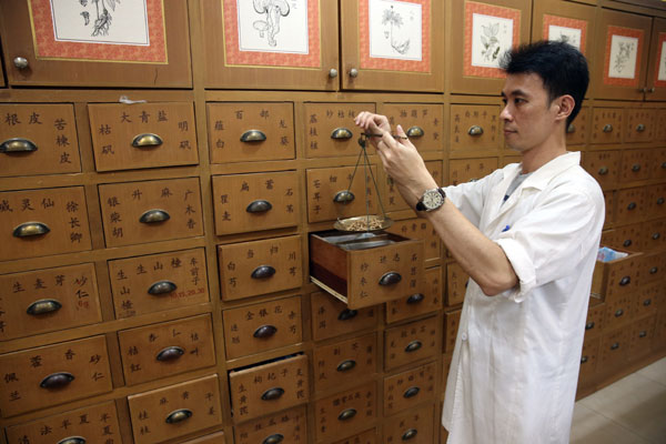 A clerk weighs traditional Chinese medicine in a Tongrentang pharmacy in Kuala Lumpur, Malaysia, in November, 2013. (Photo/China Daily)
