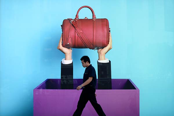 A man passes Louis Vuitton's advertisement in Wuhan, Hubei province. (Photo / China Daily)