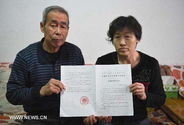 Li Sanren (L) and Shang Aiyun, parents of Huugjilt, who was wrongly executed for rape and murder at age 18, show the verdict of state compensation totaling more than 2 million yuan (about $322,000) in Hohhot, capital of north China's Inner Mongolia Autonomous Region, on Dec 31, 2014. On Dec 15, 2014, the Inner Mongolia Autonomous Regional Higher People's Court overturned Huugjilt's previous conviction and ruled he was not guilty of rape and murder, saying that the facts of his case were unclear and evidence was inadequate. (Photo/Xinhua)