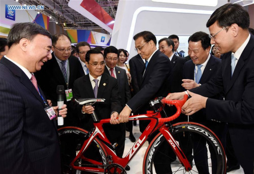 Chinese Premier Li Keqiang (3rd R, front), together with other leaders, views a bicycle made of a new-type material at an exhibition in Sanya, south China's Hainan Province, March 23, 2016. (Xinhua/Rao Aimin)