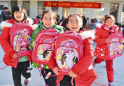 The left-behind children of Bantuan Primary School in Qiaoshan village, Luocheng Mulao autonomous county, are happy to receive new schoolbags and down jackets from local government and charitable people. (Photo: Daily/Meng Zengshi)