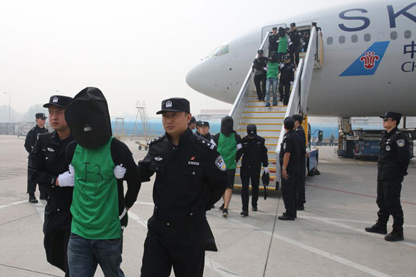 Telecom fraud suspectes are escorted off a plane by Chinese police from Kenya. (Photo/Xinhua)