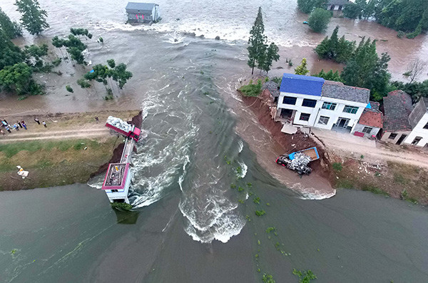Trucks loaded with stones fell into the gap of a broken dike in Huarong county, Hunan province, on Sunday. Drivers had to jump seconds before their vehicles were engulfed by the water. LI GA/XINHUA