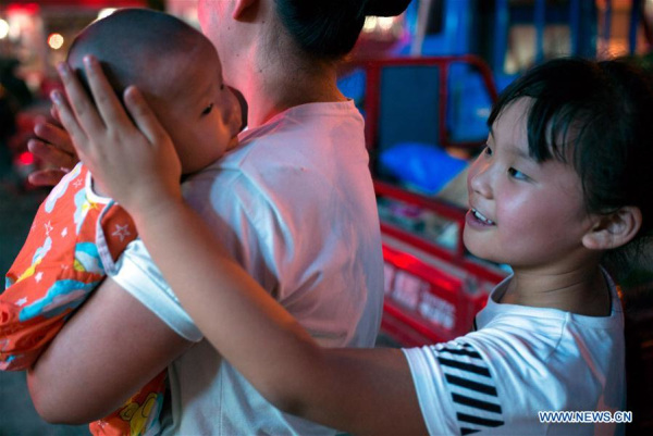 The nine-year-old Zhang Sichen (R) interacts with her three-month-old sister Zhang Yuchen in Qianshuiwan Community of Shushan District in Hefei, East China's Anhui province, July 27, 2016.(Photo/Xinhua)