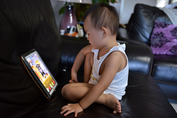 An 1-year-old baby plays a game on an iPad. (Jiang Xiaoying/For China Daily)