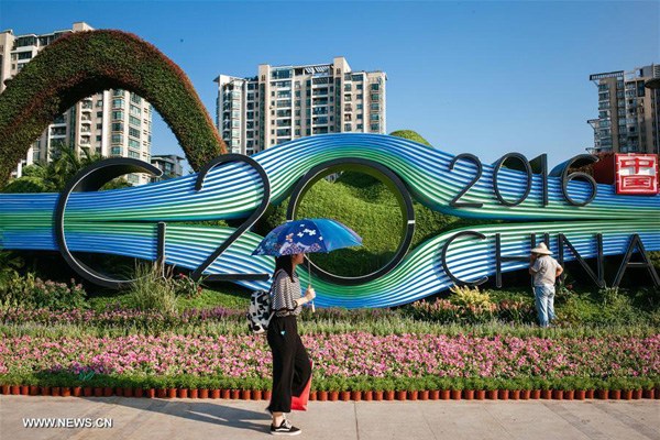 A citizen walks past a flower bed in the shape of the logo of G20 summit in Binjiang district of Hangzhou, capital city of east China's Zhejiang province, August 25, 2016. (Photo/Xinhua)