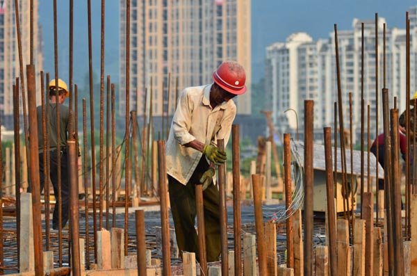 Workers at a property project in Chenzhou, Hunan province. Property developers are facing the pressure of a decline in net profits in the first half of 2014. (Photo/China Daily)