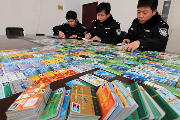 Police officers make a list of bank cards seized in a telecommunication fraud case in Xuchang, Henan province, in January.(Photo by Niu Yuan/China Daily)
