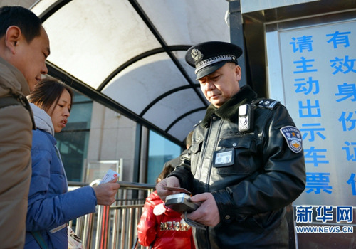 A policeman checks ID cards at Wuwei city's railway station on Feb 14. (Photo/Xinhua)