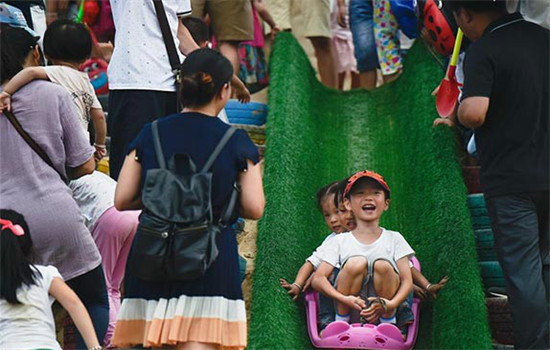 Children play with grass ski in Fuzhou, capital of Southeast China's Fujian province, Oct 2, 2016. People enjoy the second day of the week-long National Day holiday on Sunday.(Photo/Xinhua)