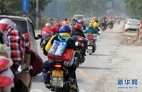 Workers ride home with their motorcycles heavily laden with Spring Festival gifts. (Photo/ Xinhua)