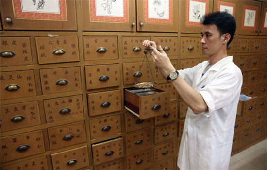 A clerk weighs traditional Chinese medicine in a Tongrentang pharmacy in Kuala Lumpur, Malaysia, in November, 2013. (Photo/China Daily)