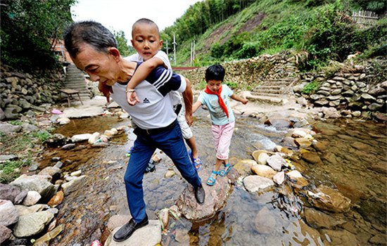 Two left-behind children follow their teacher to school in a mountainous area of Jiangxi province. (ZHUO ZHONGWEI/CHINA DAILY)