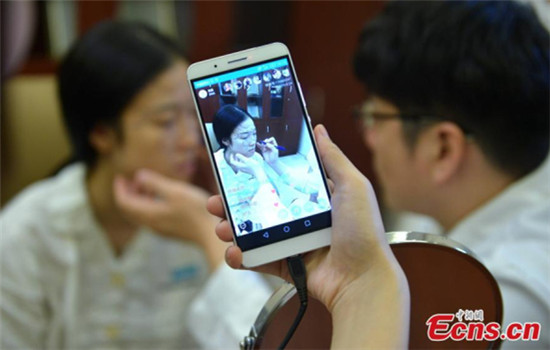 A girl from Chengdu of Southwest China's Sichuan province, talks with a doctor about her cosmetic surgery at a local hospital, Aug 24, 2016. Her friend live broadcasts her cosmetic surgery on the Internet using a cell phone at the hospital. (Photo/China News Service)