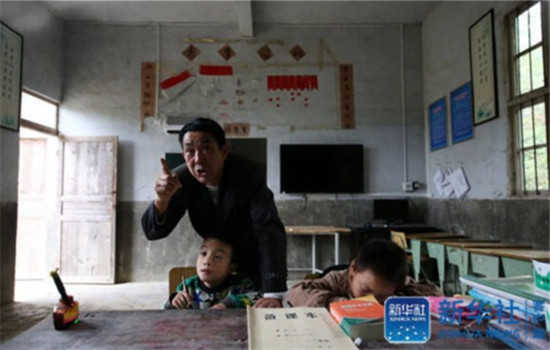 Yang Jinhua, the only teacher in Muqiao primary school, helps students with their homework on October 24, 2016. (Photo/Xinhua)