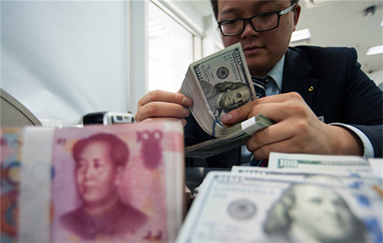 An employee at a bank counter in Nantong, Jiangsu province, counts renminbi and dollars. (Photo/China Daily)