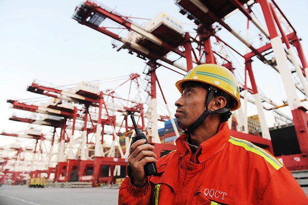 A worker looks closely as containers are unloaded in Qingdao Port, Shandong province. (Photo/China Daily)