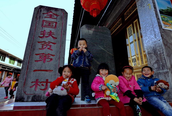 Children of She ethnic group sit in front of a monument that reads China's No. 1 Poverty Relief Village at Chixi Village, Panxi town, Fuding city in East China's Fujian province, Feb 14, 2016. The village has shaken off poverty thanks to assistance from Party and government officials at all levels over the past 30 years. (Photo/Xinhua)