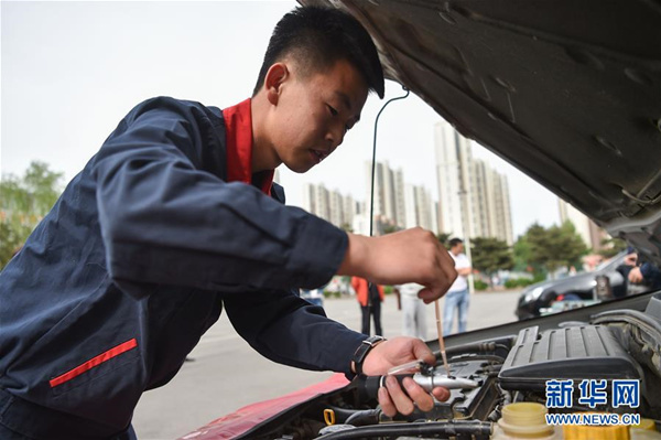 A student majoring in automobile maintenance at the Inner Mongolia Economics and Trade School competes in the vocational skills competition, on May 13. (Photo/Xinhua)