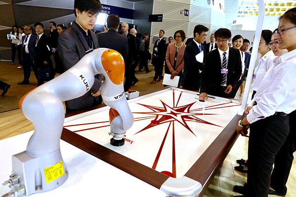 A man playing with a robot during the World Economic Forum, June 27. (Photo by Zhu Xingxin/China Daily)