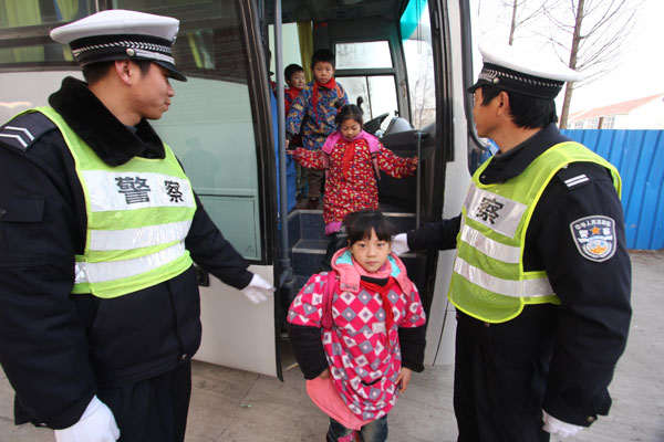 Two police officers count students getting off a school bus to see if it is overloaded in Xuwei district of Lianyungang, Jiangsu province, on Dec 17, 2011. (Photo by Mu Daoyong / for China Daily)
