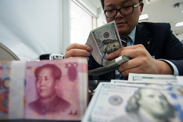 An employee at a bank counter in Nantong, East China's Jiangsu province, counts renminbi and dollars. (Photo/China Daily)