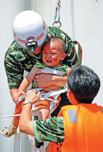 Rescuers save a child trapped by floods in Benxi, Liaoning province, on Monday. 