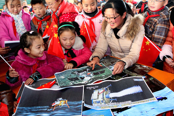 Students learn about the ongoing Change-3 mission at a primary school in Ganyu, Jiangsu province, on Tuesday. Designers are pleased with the mission's success so far, as experiments have gone more smoothly than expected. Si Wei / for China Daily