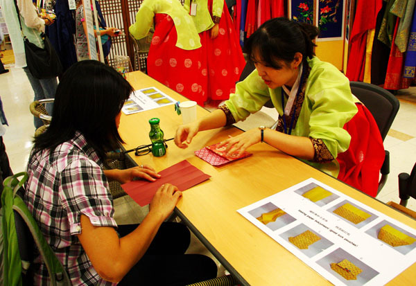 A Chinese tourist learns how to fold a Korean lucky bag at the exhibition hall of Korea Tourism Organization in Seoul. (Photo/Xinhua)