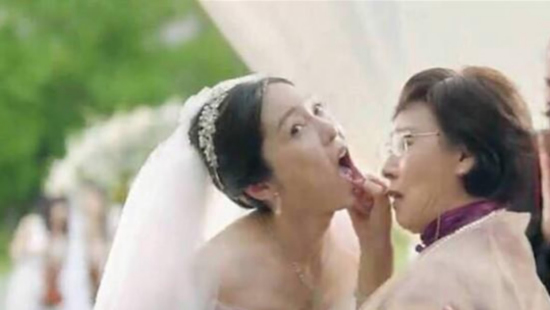 A screenshot from the controversial commercial clip where a mother-in-law is inspecting a bride during the wedding for signs that give away her undergoing plastic surgery.