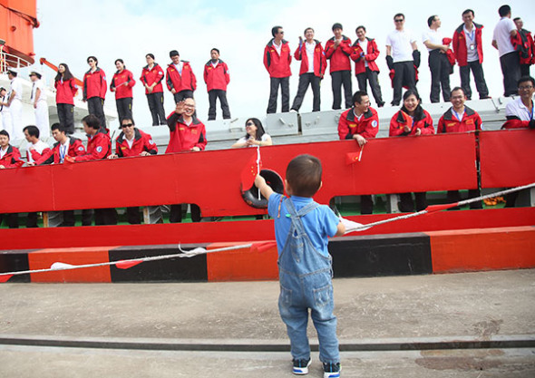 Shi Xing'an, a member of China's eighth Arctic expedition team, waves to his son from the deck of icebreaker Xuelong at a port in Shanghai on Tuesday. The boy was welcoming him home after a 20,000-nautical-mile voyage over 83 days. (Gao Erqiang/China Daily