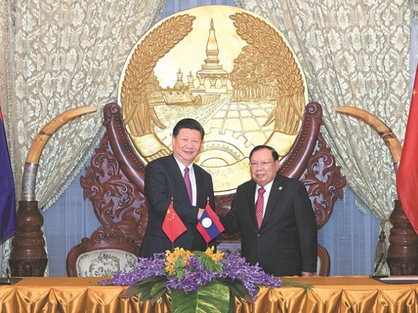 President Xi Jinping and his Laotian counterpart Bounnhang Vorachith shake hands in Vientiane, Laos, on Monday at the signing ceremony for documents to boost cooperation between the countries. (WANG YE / XINHUA)
