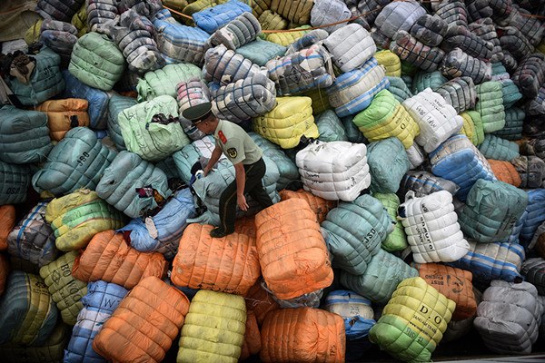 A border guard in Shenzhen, Guangdong province, inpects bundles of waste textiles smuggled into China. (Photo/Xinhua)