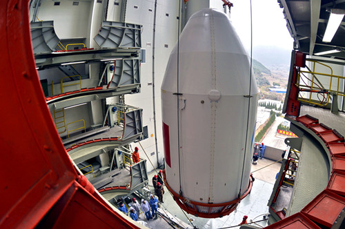Technicians at the Xichang Satellite Launch Center, Sichuan province, and employees of China Aerospace Science and Technology Corp hoist a payload fairing before assembling a carrier rocket on a launchpad at the center. [Provided to China Daily]