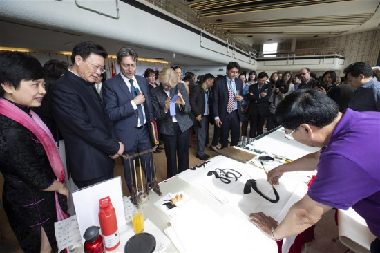 Francesco Pisano (3rd L, Front), Director of the Library, United Nations Office at Geneva (UNOG), and Yu Jianhua (2nd L, Front), China's Permanent Representative to the UNOG, watch a Chinese calligraphy show during the exhibition Charm of Chinese Culture: from Characters to Literature at Palais des Nations in Geneva, Switzerland, on April 16, 2018. (Xinhua/Xu Jinquan)