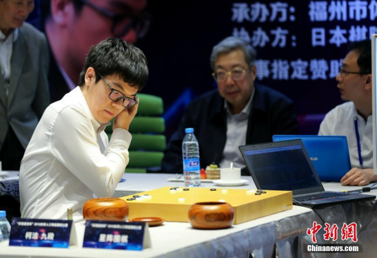 Ke Jie (L) is playing Go with Golaxy, a Chinese-developed AI program. (Photo: China News Service/Wang Dongming)