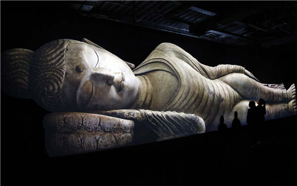 Visitors admire the image of a reclining Buddha that was presented using 3D technology during an exhibition in Shanghai on Wednesday. The exhibition, which features images from the Mogao Grottoes, presents 100 artifacts related to the ancient Silk Road. It opened on Saturday and will run for 10 months. (Photo/China News Service)