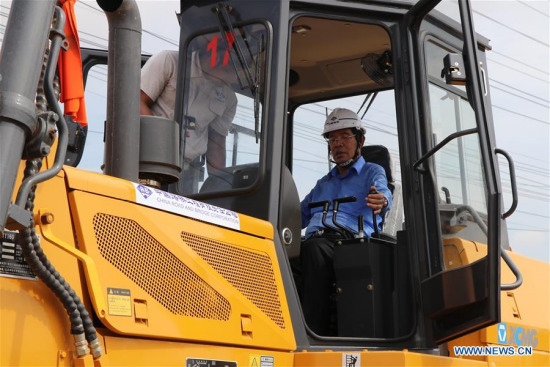 Cambodian Prime Minister Samdech Techo Hun Sen (R) operates a bulldozer during the groundbreaking ceremony in Phnom Penh, Cambodia, on May 7, 2018. (Xinhua/Mao Pengfei)