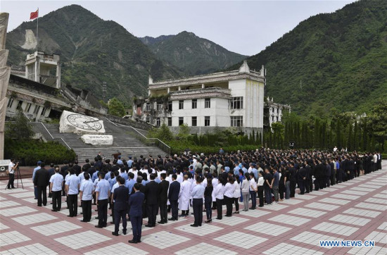 People gather at the ruined site of Xuankou Middle School as they participate in a memorial ceremony marking the 10th anniversary of the Wenchuan Earthquake in Yingxiu Township of Wenchuan County, southwest China's Sichuan Province, May 12, 2018.(Xinhua/Liu Kun)
