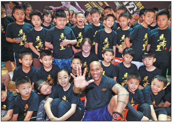 Former NBA All-Star Stephon Marbury, co-founder and head coach of the new Stronger Me Basketball Training Camp, poses with young players at Sunday's launch in Beijing. (Photo provided to China Daily)