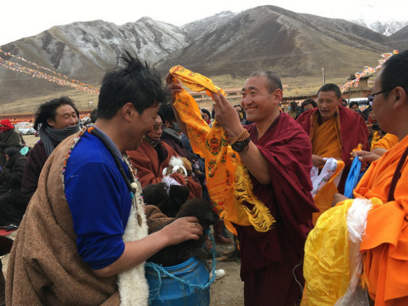 A Buddhist monk salutes a local herder who just adopted a dog. (Photo provided to China Daily)