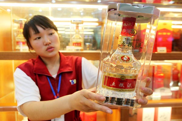 A sales assistant showcases a bottle of Wuliangye white spirits at a supermarket in Ganyu county, Jiangsu province. [Provided to China Daily]