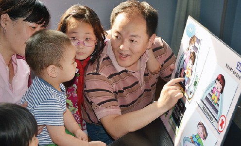 Otis volunteer Hao Yong (right) and his daughter Hao Yiran (second right) instruct children in Tianjin about escalator safety. (Photo provided to China Daily)