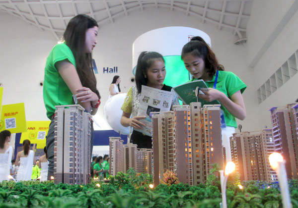 Saleswomen promote a property at a housing fair in Haikou, Hainan province. (Photo/China Daily)