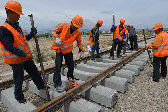 Workers lay track for the Korla-Golmud Railway in the Xinjiang Uygur autonomous region on Saturday. (Que Hure / For China Daily)