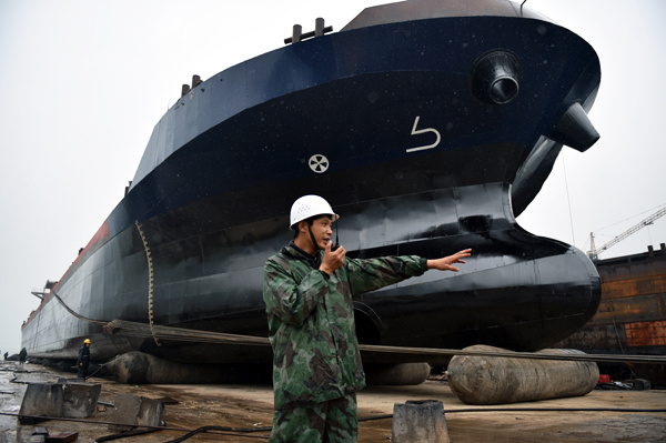 A technician directs the hauling of a ship at a shipyard in Chongqing. (Photo by Rao Guojun/For China Daily)