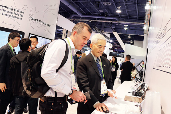 Staff ers of the Kangde Xin Composite Material Group Co Ltd from China's Jiangsu province shows the company's glasses-free 3D notebook to visitors at the CES 2018 in Las Vegas on Wednesday. The company has more than 800 glasses-free 3D patents. (ZHOU PAI / CHINA DAILY)
