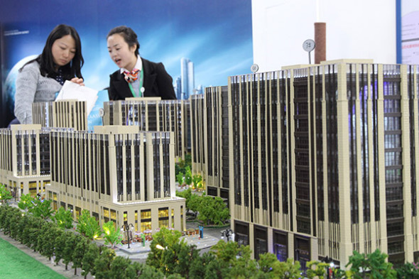  Visitors look at a model of a housing project at a real estate exhibition in Beijing. (Photo provided to China Daily)